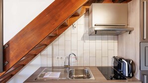 Eine Küche mit Spüle aus Edelstahl, einer eingebauten Dunstabzugshaube und einem Toaster auf der Arbeitsfläche.