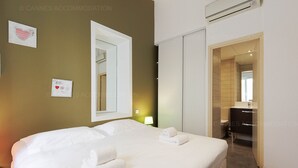 A hotel room with a large bed, a bedside table with a lamp, a mirror, and a bathroom visible through an open door. - Residence Aout 43-2870-Beautiful 1-bedroom apartment ideally located (Cannes)