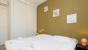 A neatly made bed with rolled towels, a bedside lamp, and artwork on the wall. - Residence Aout 31-2872-Beautiful 2-bedroom apartment ideally located (Cannes)
