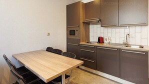 A modern kitchen with a wooden table and chairs, a built-in oven, a microwave, and a kettle. - Residence Aout 31-2872-Beautiful 2-bedroom apartment ideally located (Cannes)