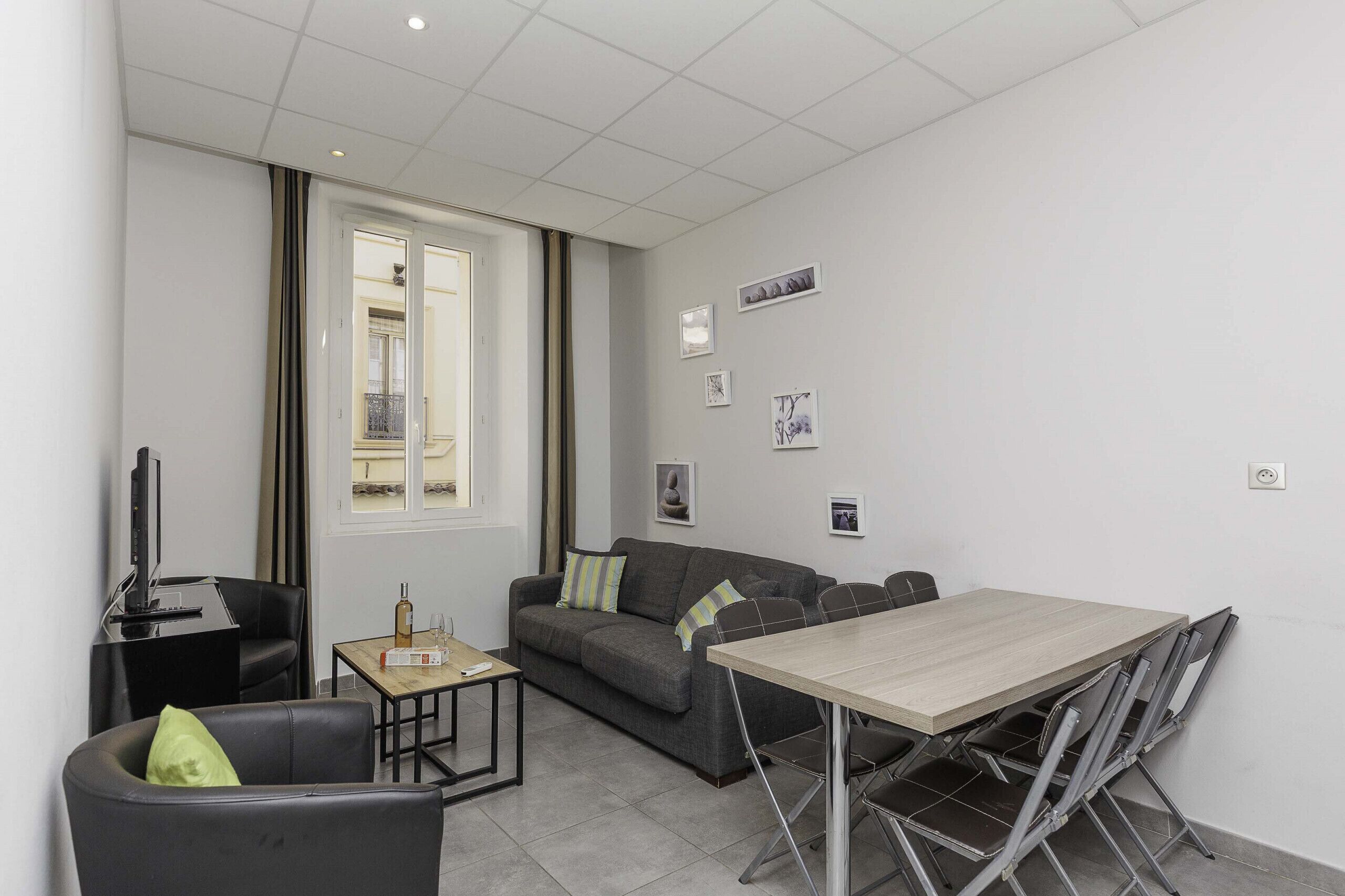 Ein modernes Wohnzimmer mit Sofa, Couchtisch, Fernseher und einem Esstisch mit Stühlen.