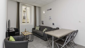 Un soggiorno moderno con un divano, un tavolino, una TV e un tavolo da pranzo con sedie.