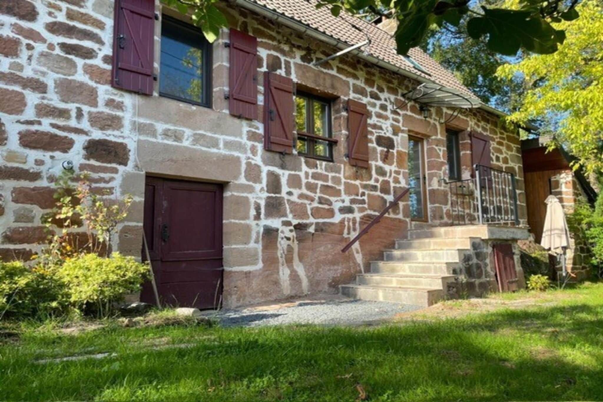 Ein Steinhaus mit einer Holztreppe, die zu einer Tür führt.