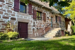 A stone building with a wooden staircase leading to a door. - Cottage in Corrèze with Garden Views (LOUIGNAC)