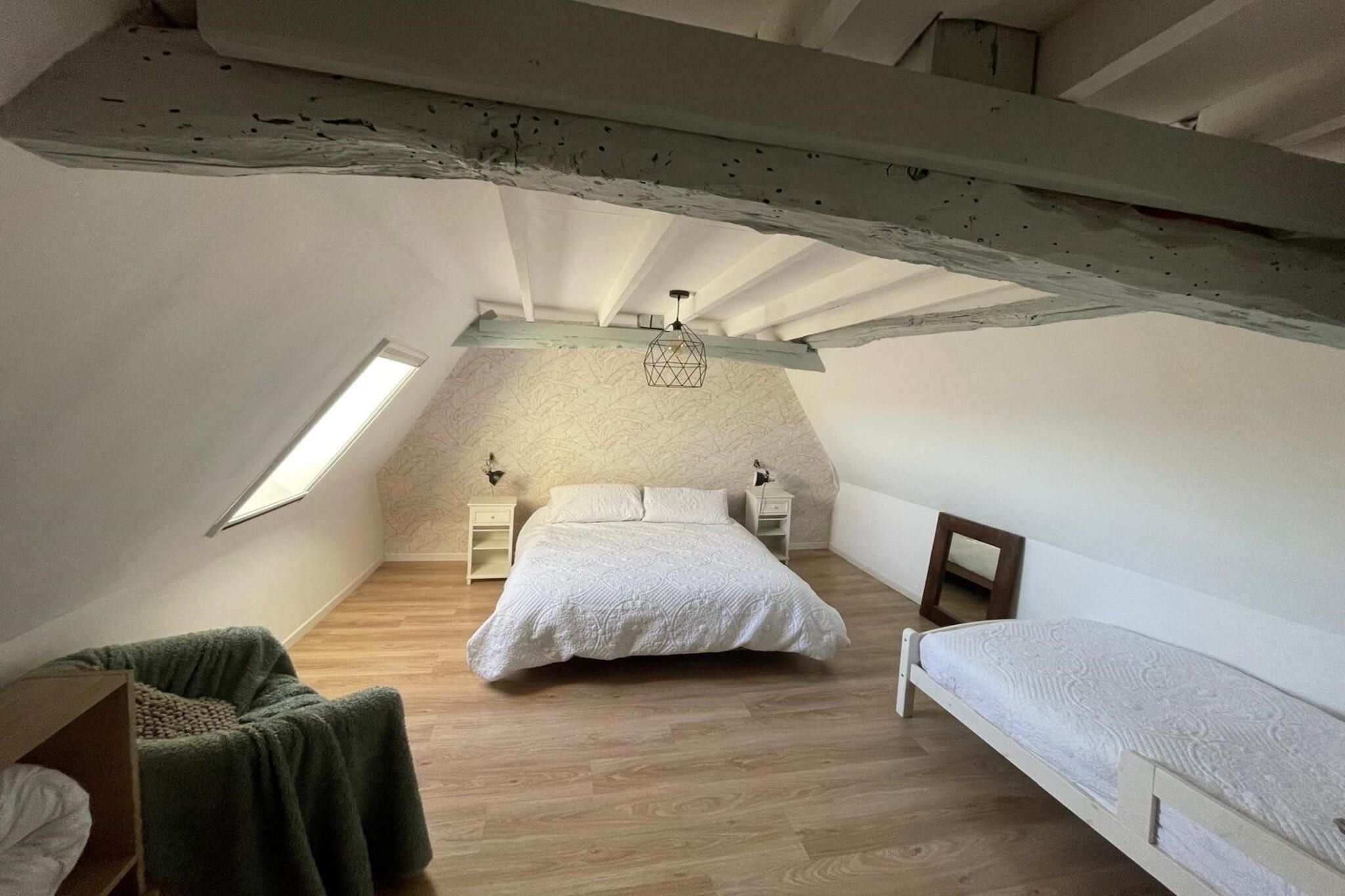 Ein Schlafzimmer mit schrägen Wänden, einem Bett, einem Sessel und einem kleinen Tisch.
