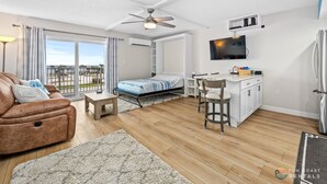 Een moderne woonkamer met een bank, een eethoek, een bed en een keuken met een koelkast en een televisie.