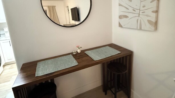 A room with a wooden desk, two chairs, a round mirror, and a leaf-patterned artwork on the wall. - Private entrance in-law apartment located minutes from WEC-Ocala. (Ocala)