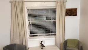 A living room with two grey armchairs, a white coffee table with a bird sculpture, a window with blinds, and a wall-mounted artwork. - Private entrance in-law apartment located minutes from WEC-Ocala. (Ocala)