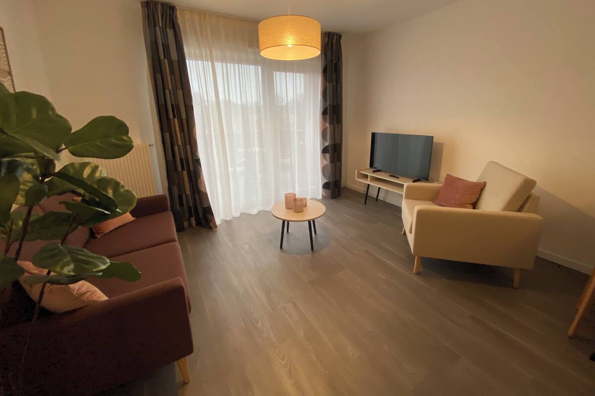 Una sala de estar moderna con sofá, sillón, televisor y una mesita con velas.