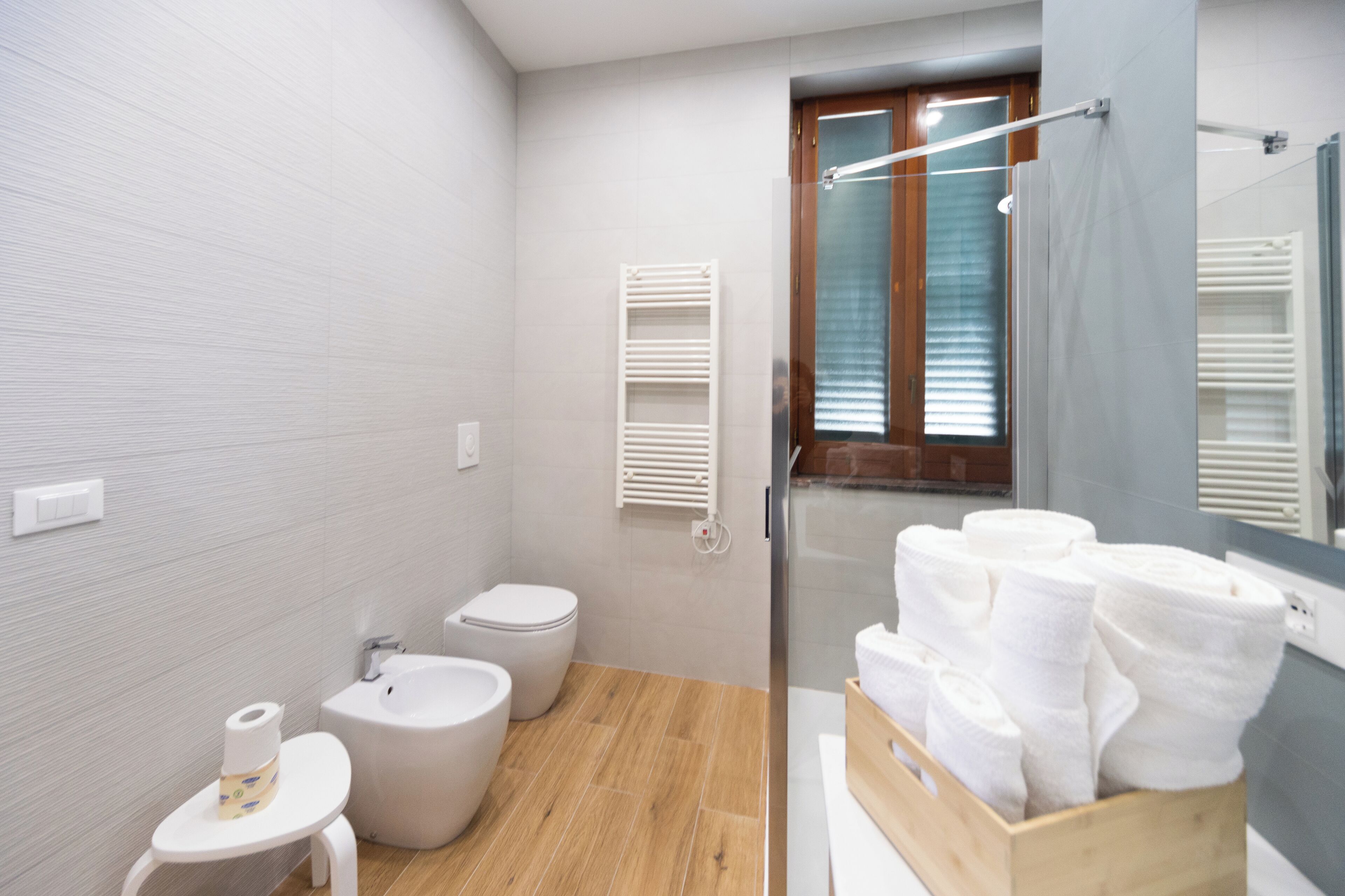 A modern bathroom with a bidet, toilet, and a wooden vanity with towels.