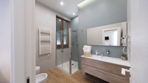 Een moderne badkamer met een douchecabine van glas, een houten wastafelmeubel en een grote spiegel.