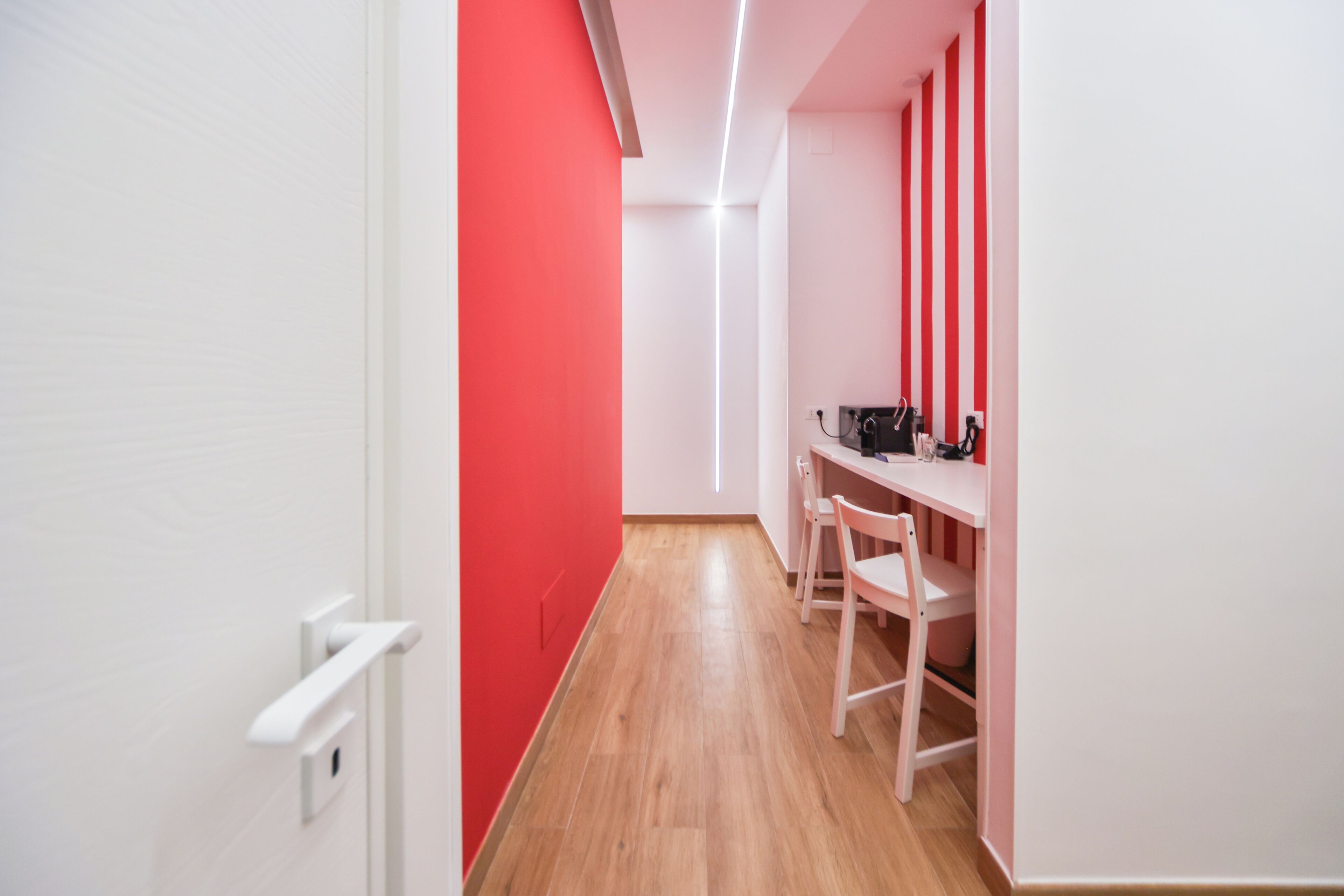 Un couloir étroit doté d’un plancher en bois et d’un mur rouge sur un des côtés.