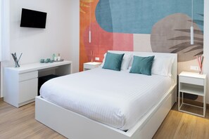 Ein modernes Schlafzimmer mit einem großen Bett, einem Schreibtisch und einem an der Wand befestigten Fernseher.