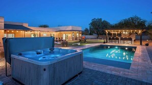 A hot tub and a swimming pool in a backyard with a covered seating area and lounge chairs. - Resort-Style Escape: Pool, Courts, and Endless Fun (Scottsdale)