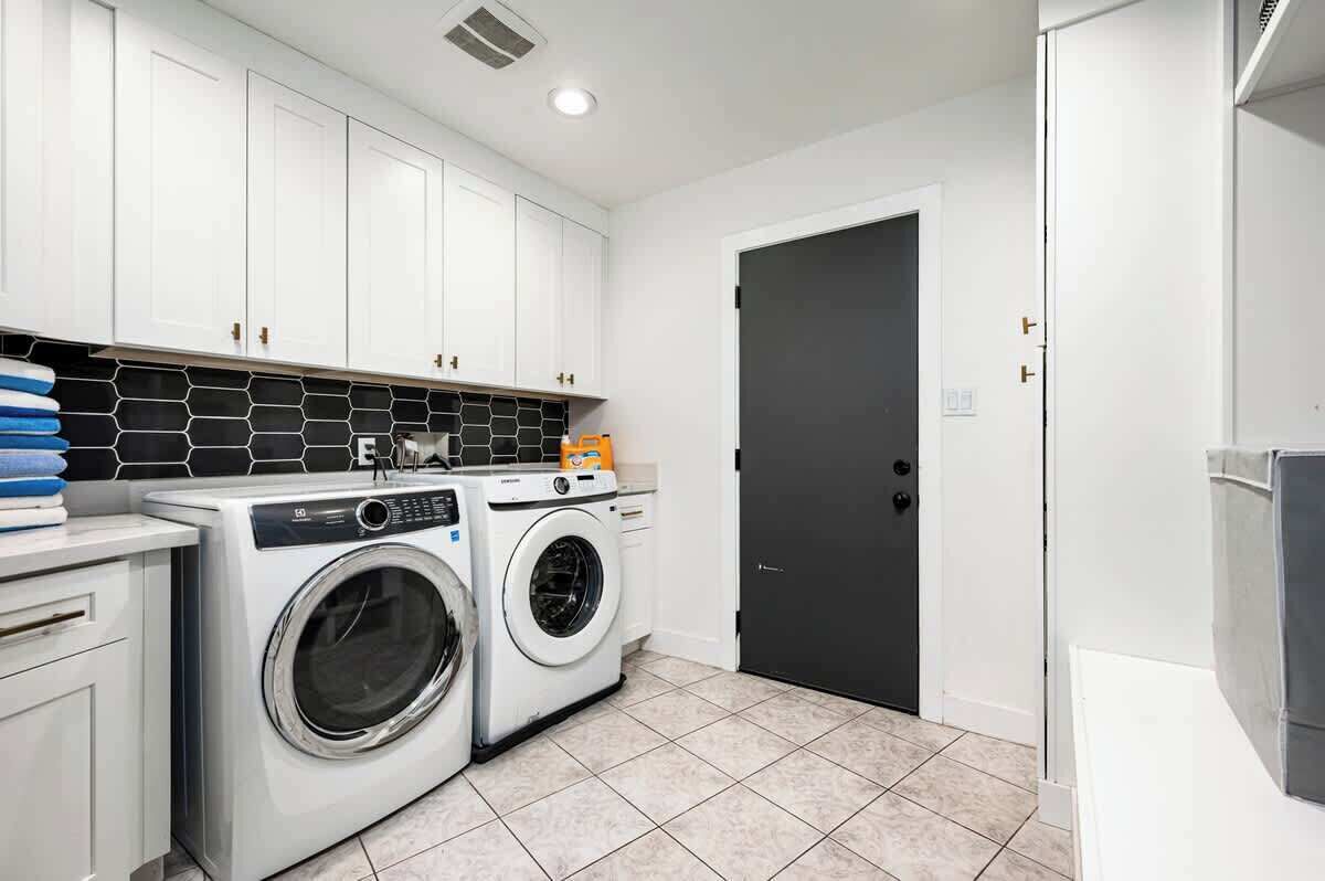 A laundry room with a washing machine, dryer, and stacked laundry.