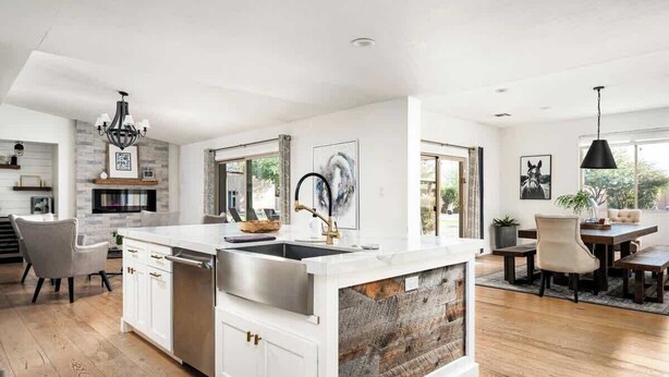 A modern kitchen with white cabinetry, a large island, and a dining area with a wooden table and chairs. - Resort-Style Escape: Pool, Courts, and Endless Fun (Scottsdale)