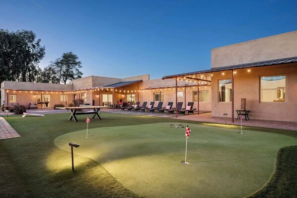 En bygning med patio, udendørs møbler og en putting green.