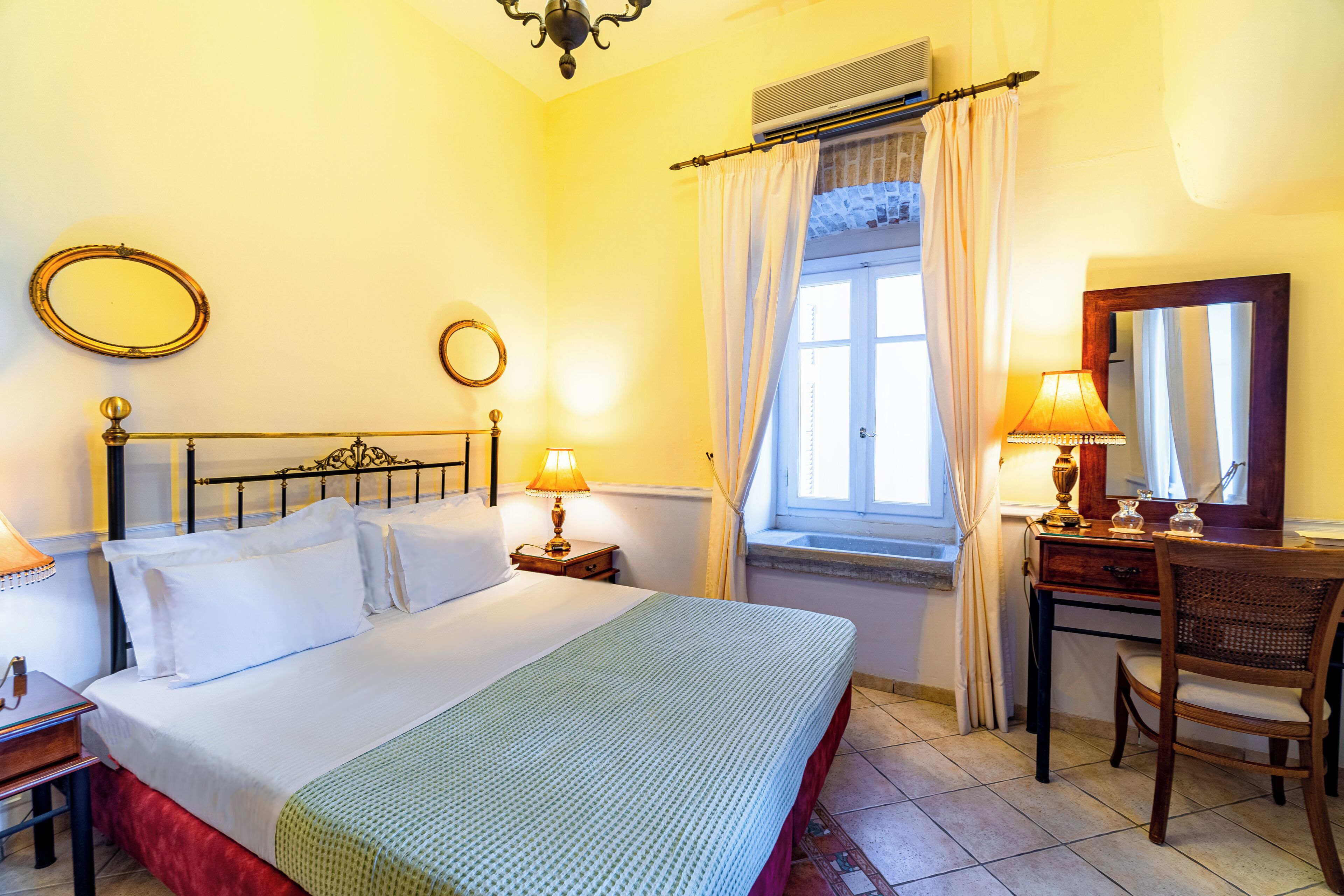 A neatly arranged bedroom with a bed, bedside tables, a desk, and a chair.