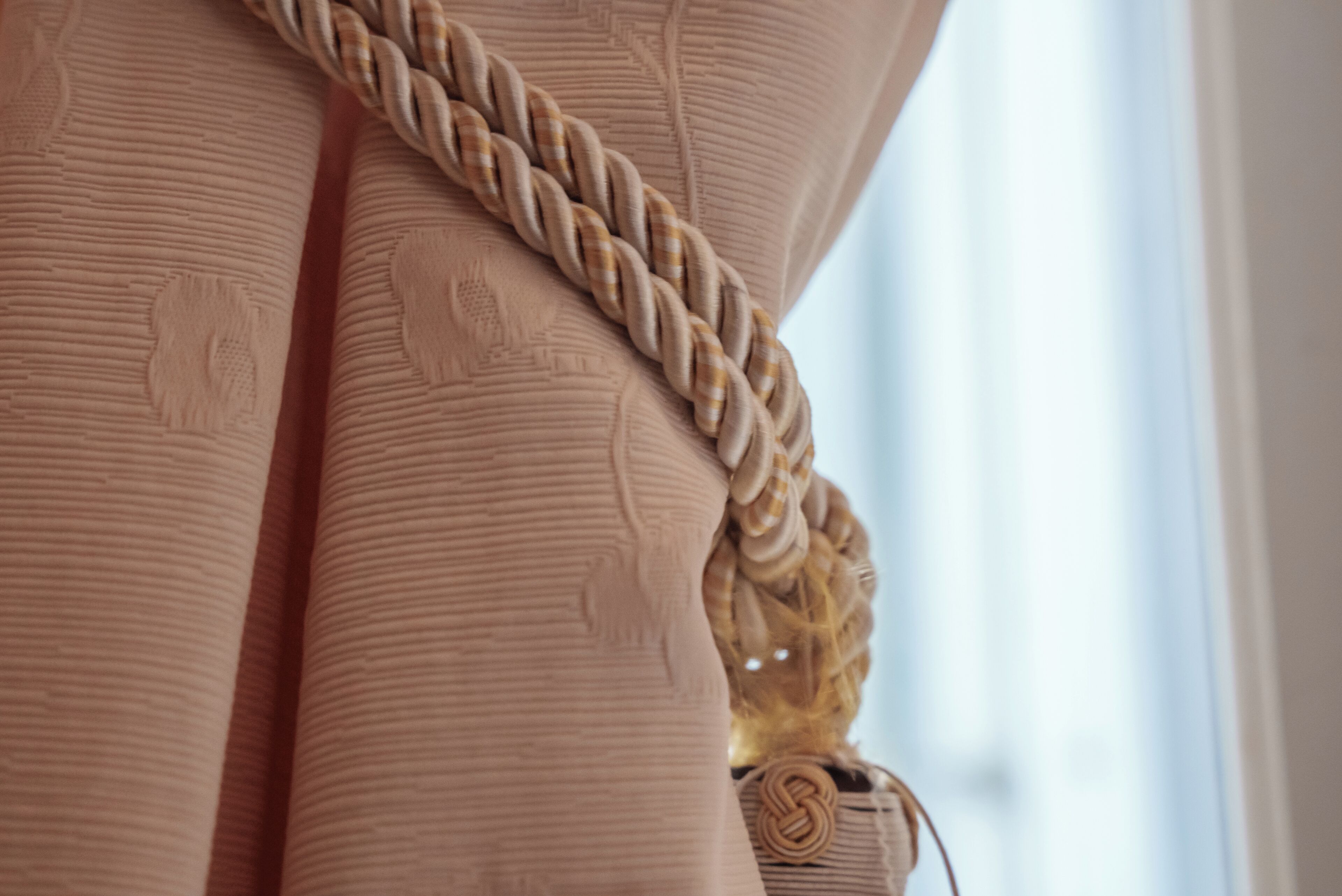 A close-up of a textured fabric with a braided belt detail.