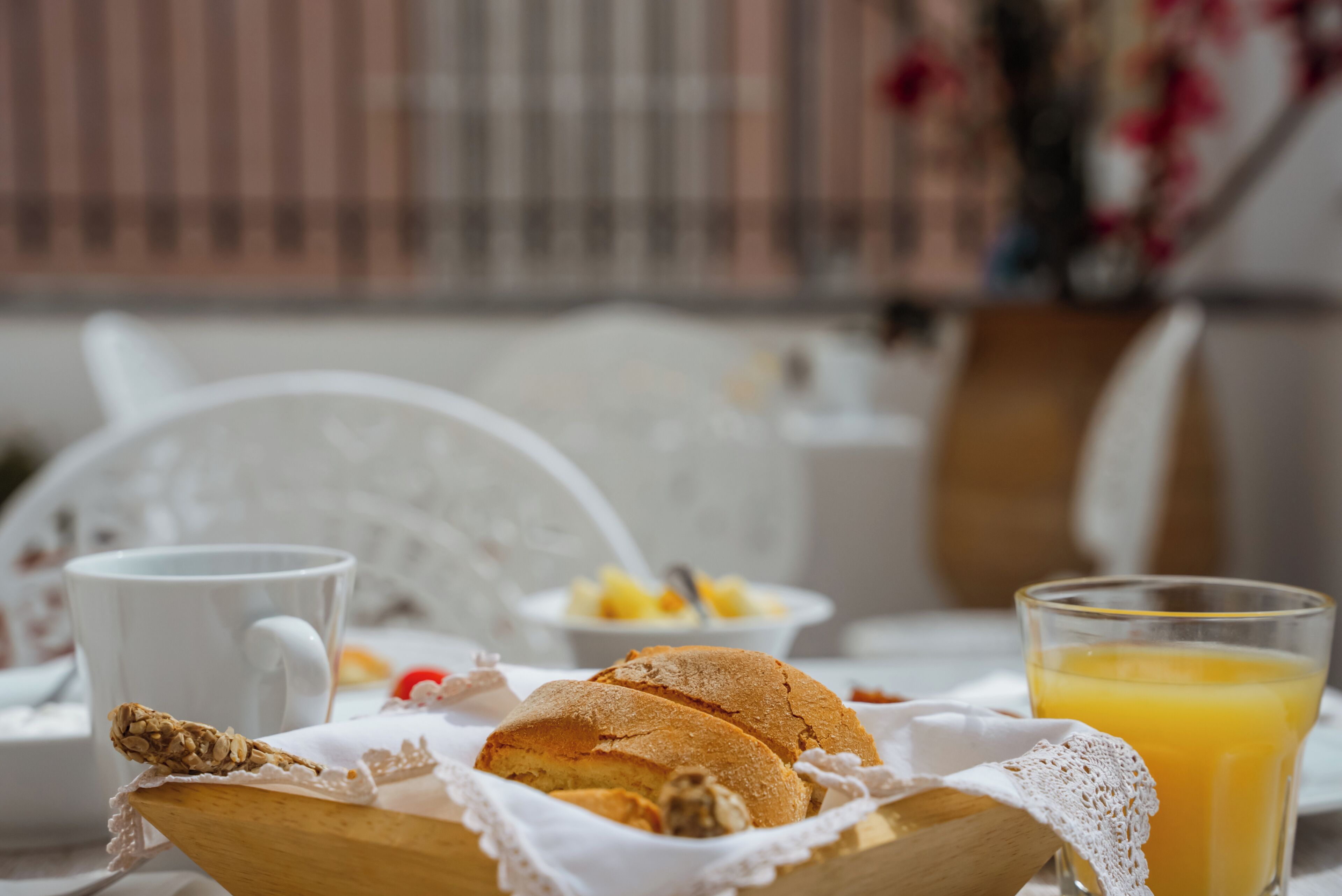 Desayuno con pan, una taza y un vaso de jugo de naranja sobre una mesa.