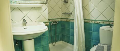 Un baño con lavamanos, ducha e inodoro.