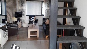 Uma sala de estar moderna com escada, lareira e televisão.