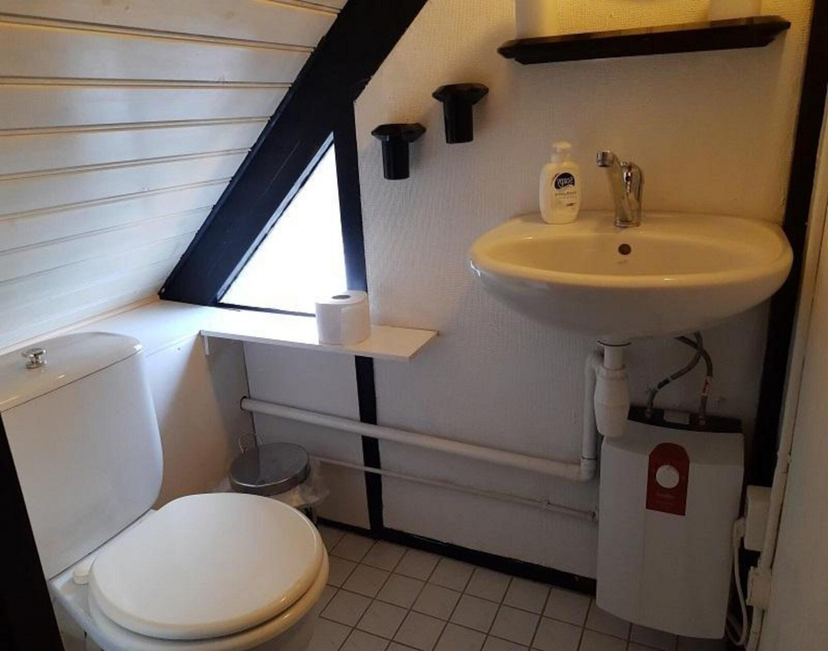 A compact bathroom with a toilet, sink, and window.