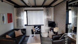 Uma sala de estar moderna com um sofá de couro preto, uma mesa de centro de madeira e uma parede com padrão preto e branco.