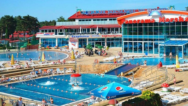 Un'ampia area con piscina esterna, dotata di più piscine, un ristorante e un edificio con tetto rosso.