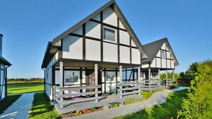 Un edificio moderno con un'ampia veranda, diverse finestre e un vialetto che conduce all'ingresso.