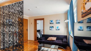 Un soggiorno moderno con divano, tavolino, paravento decorativo e opere d'arte alle pareti.