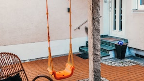 Un’altalena, una sedia in vimini e una porta con una finestra.