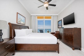 A bedroom with a bed, a nightstand, a dresser, a television, and a ceiling fan.