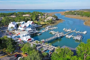 A marina with boats docked, a pier, and a waterfront hotel with multiple buildings and a covered area.