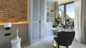 Ett modernt rum med en tegelvägg, ett vitt skåp med skjutdörrar, ett matbord med stolar och en balkong med utsikt.