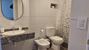 Une salle de bain équipée d’un lavabo, d’un bidet, de toilettes et d’un miroir.