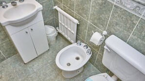 Une salle de bain équipée d’un lavabo, d’un bidet, de toilettes et d’un radiateur.