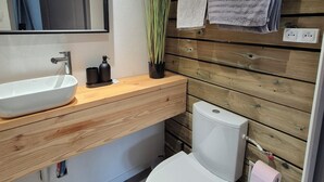 A modern bathroom with a wooden vanity, white sink, and toilet.