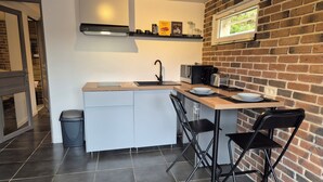 A compact kitchen with a sink, microwave, toaster, and a small dining area with two chairs.