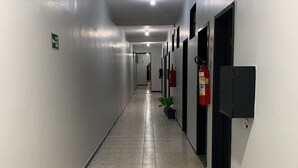 A long, narrow hallway with tiled flooring, white walls, and doors on one side. - hotel Taguatinga sul (Taguatinga)
