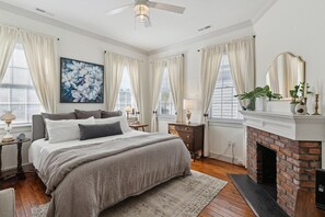 A bedroom with a bed, a fireplace, and a large window with curtains.