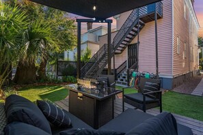Une terrasse extérieure dotée d’un foyer, de sièges et d’un escalier menant à un bâtiment.