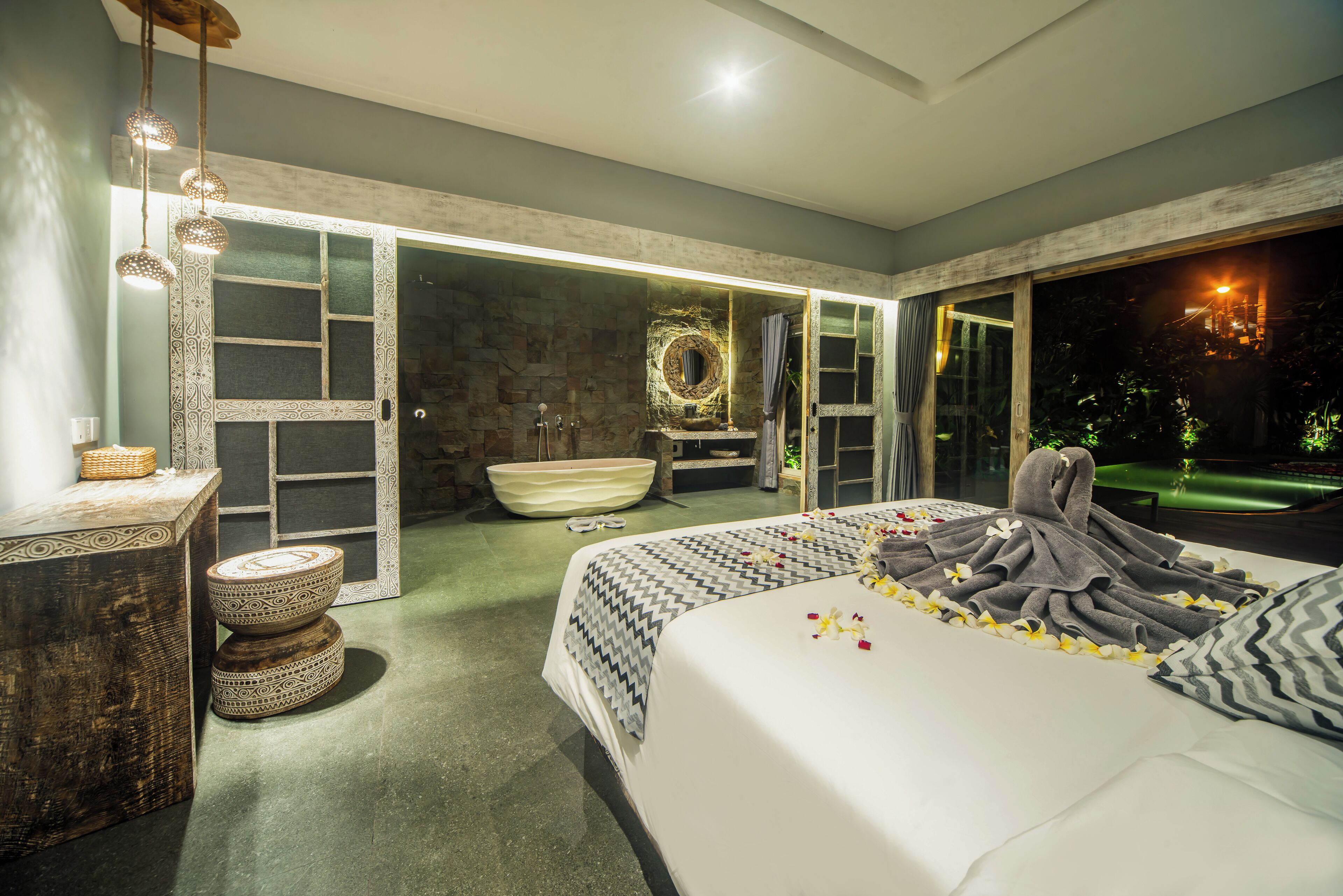 Un dormitorio moderno con una cama grande, un tocador con espejo y vistas al exterior.