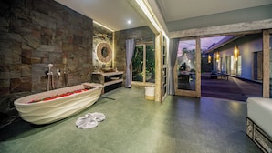 Een moderne badkamer met een vrijstaand bad, stenen muur en uitzicht op het buitengebied.