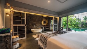 Een ruime slaapkamer met een groot bed, een inloopbad en uitzicht op een zwembad.