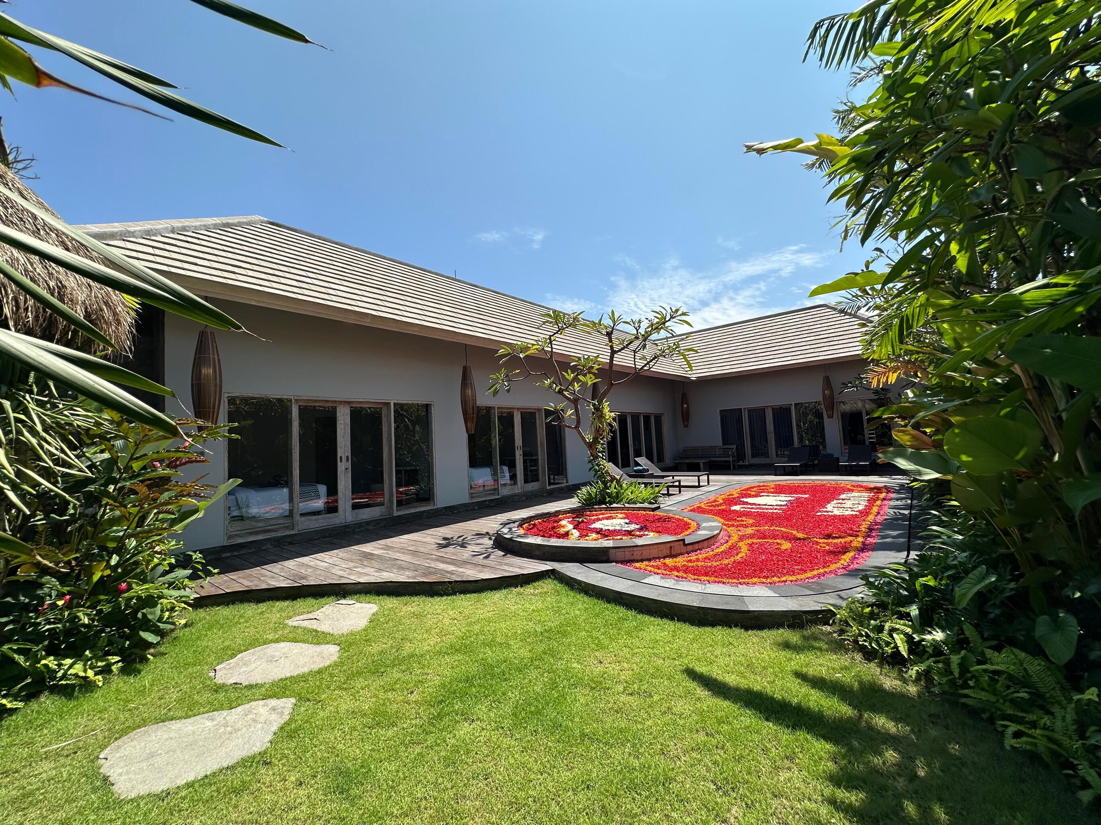 Une maison moderne dotée d’une pelouse bien entretenue, d’un parterre circulaire et d’une structure à toit de chaume.