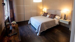 A modern hotel room with a large bed, bedside lamps, a wooden nightstand, and a mirror with flowers. - Ludo's House (Napoli)