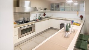 A modern kitchen with stainless steel appliances, a central island, and pendant lighting. - Ludo's House (Napoli)