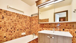 A bathroom with a bathtub, a sink, and a mirror. - Apartment Mont d'Arbois Megeve - Ski in/out (Megève)