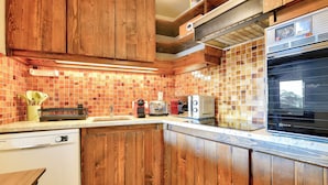 A kitchen with wooden cabinets, a tiled backsplash, and a built-in oven. - Apartment Mont d'Arbois Megeve - Ski in/out (Megève)
